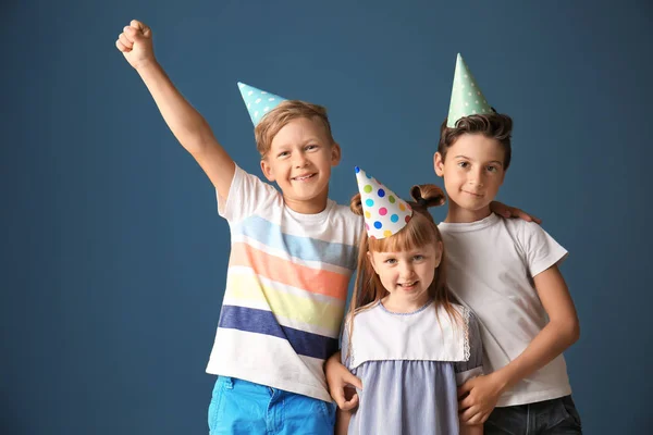 Cute little children in Birthday hats on color background