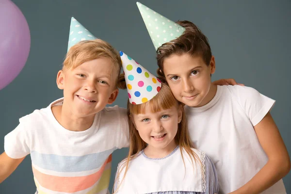 Cute little children in Birthday hats on color background