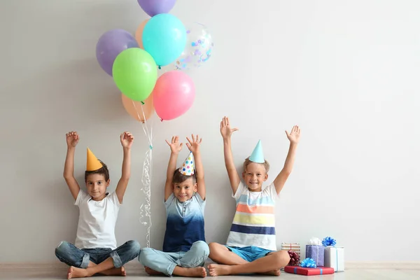 Lindos Niños Pequeños Sombreros Cumpleaños Sentados Suelo Cerca Pared Luz —  Fotos de Stock