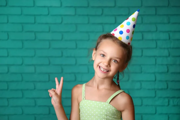 Schattig Klein Meisje Verjaardag Hoed Tegen Kleur Bakstenen Muur — Stockfoto