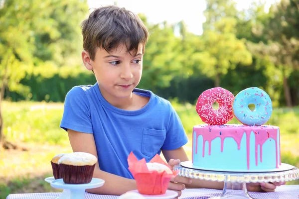 Cute little boy with cake celebrating Birthday outdoors