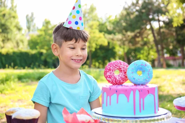 Cute little boy with cake celebrating Birthday outdoors