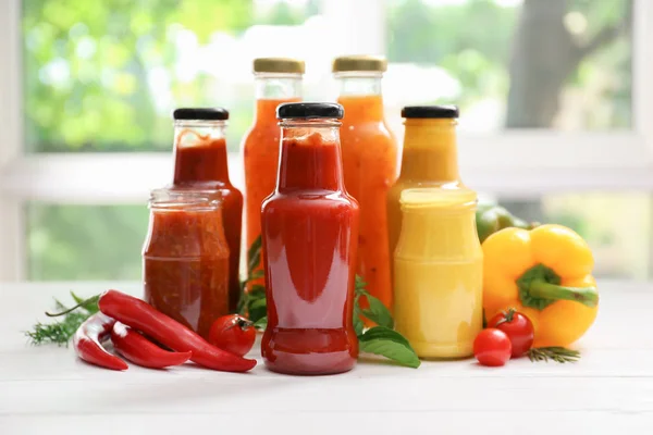 Gläser Mit Verschiedenen Leckeren Saucen Und Gemüse Auf Weißem Tisch — Stockfoto