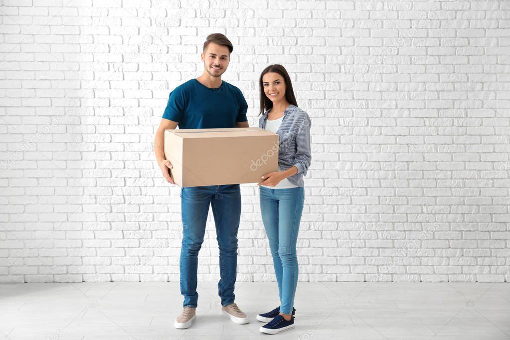 Young couple with moving box at new home
