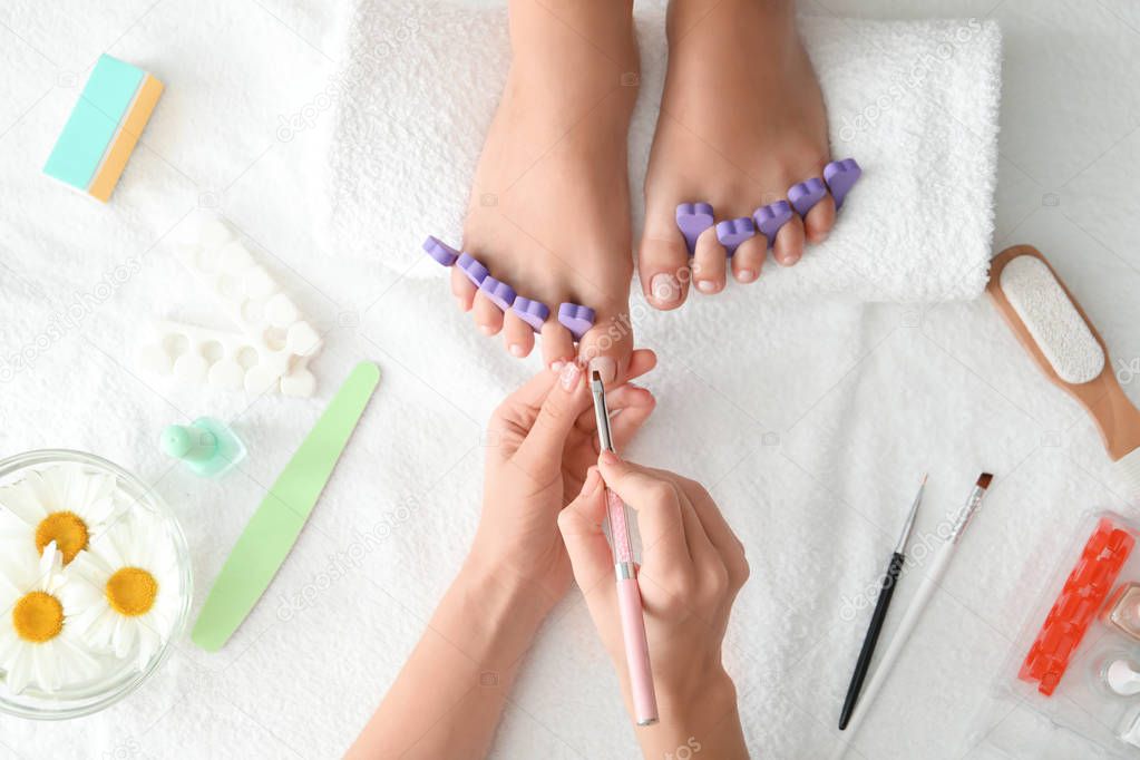 Young woman getting professional pedicure in beauty salon