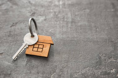 Biblo koyu arka plan üzerinde ev şeklinde anahtarla. İpotek kavramı