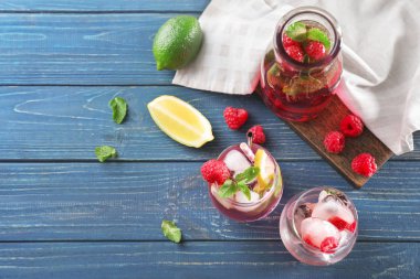 Gözlük ve ahşap masa üzerinde taze ahududu mojito şişe