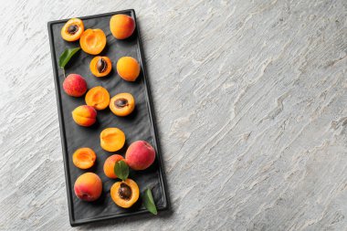 Beyaz ahşap zemin üzerinde olgun tatlı kayısı ile plaka