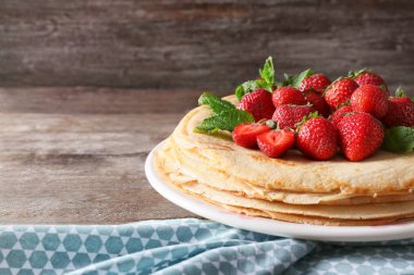 Lezzetli ince krep ve ahşap masa üzerinde meyveleri ile plaka