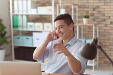 Ofiste cep telefonuyla konuşan yakışıklı genç adam.