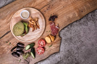 Ahşap masa üzerinde kızarmış patates ile lezzetli yeşil burger