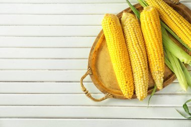 Ahşap arka plan üzerinde lezzetli mısır koçanı ile tepsi