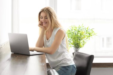 Kafede dizüstü bilgisayar kullanan genç bir kadın