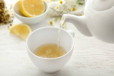 Lezzetli papatya çayı fincan içine ahşap masanın üstüne dökme.