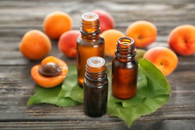 Esans ve ahşap masa üzerinde taze kayısı ile şişe