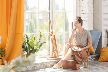 Atölye penceresinde yakınındaki ilham için bekleyen kadın sanatçı