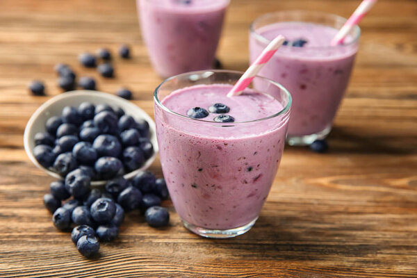 Glasses of tasty blueberry smoothie on wooden table