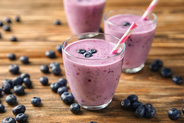 Glasses of tasty blueberry smoothie on wooden table