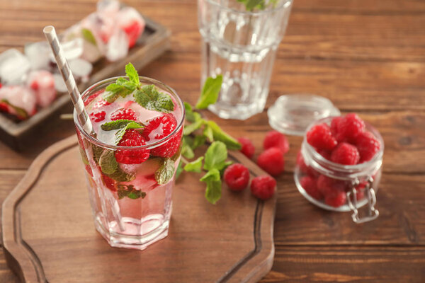 Glass of fresh raspberry mojito on board