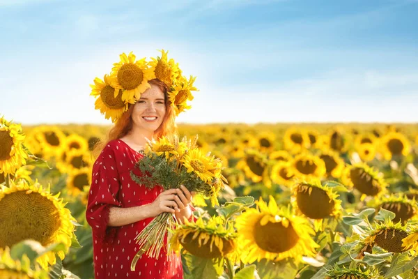 Beautiful redhead woman in sunflower field on sunny day