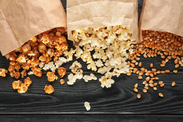 Paper Bags Scattered Delicious Popcorn Kernels Wooden Background — Stock Photo, Image
