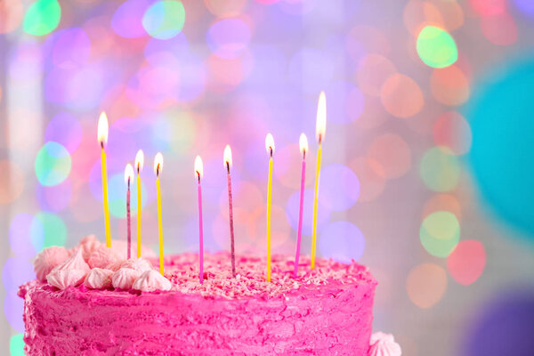 Вкусный праздничный торт и горящие свечи против размытых огней, крупным планом
