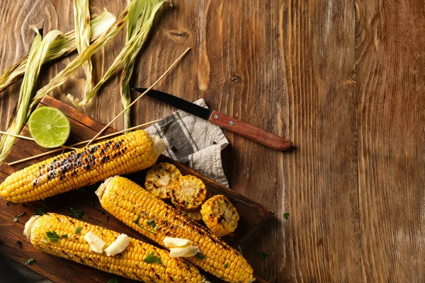 Tasty grilled corn cobs on wooden table