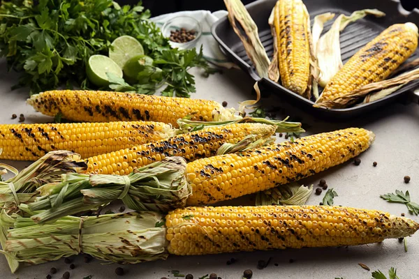 Tasty grilled corn cobs on grey table