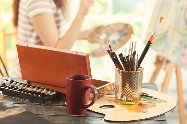 Table with brushes and paints in artist\'s workshop