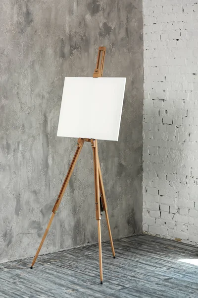 Easel with canvas near wall in artist's workshop