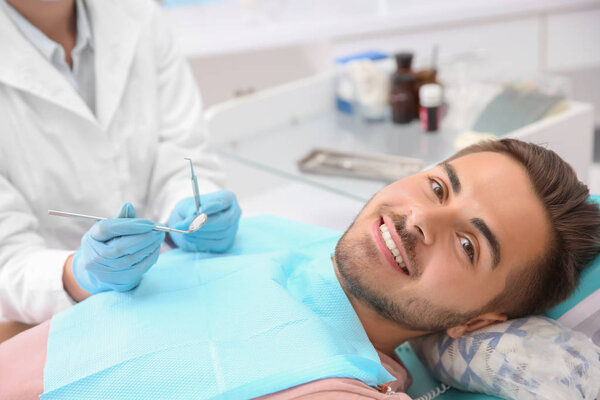 Стоматолог, осматривающий зубы пациента в клинике