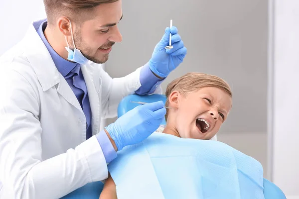 牙医试图检查在诊所淘气的小男孩的牙齿 — 图库照片