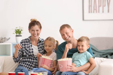 Mutlu aile evde Tv izlerken patlamış mısır yemek