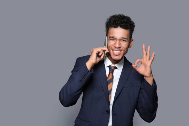 Yakışıklı Afrikalı-Amerikalı işadamı tarafından cep telefonu gri arka plan üzerinde konuşurken