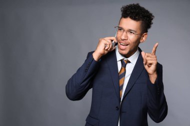 Yakışıklı Afrikalı-Amerikalı işadamı tarafından cep telefonu gri arka plan üzerinde konuşurken
