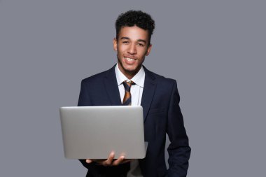 Gri arka plan üzerinde dizüstü bilgisayar ile yakışıklı Afrikalı-Amerikalı işadamı