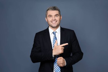 Yakışıklı işadamı gri arka plan üzerine bir şey işaret