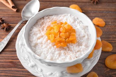 Lezzetli sütlaç ve ahşap masa üzerinde kuru kayısı ile kase