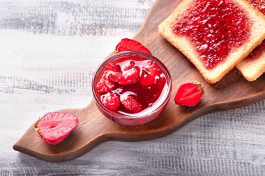 Kurulu ile dilim ekmek ve ahşap masa üzerinde lezzetli çilek reçeli