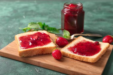 Kurulu ile dilim ekmek ve yeşil masada, closeup lezzetli çilek reçeli