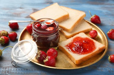 Dilim ekmek ve ahşap masa üzerinde lezzetli çilek reçeli ile plaka