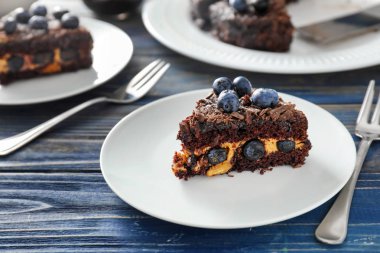 Ahşap masa üzerinde yaban mersini çikolatalı kek parçası ile plaka