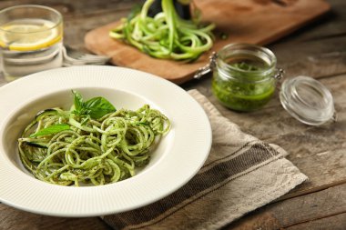 Tabak spagetti ahşap masa üzerinde kabak ve pesto sos ile