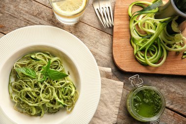 Tabak spagetti ahşap masa üzerinde kabak ve pesto sos ile