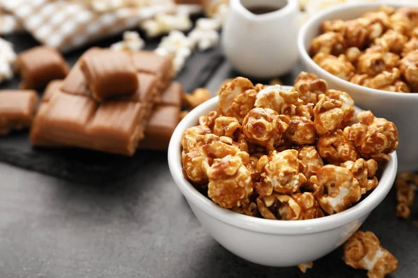 Bowl with delicious caramel popcorn on grey table, closeup