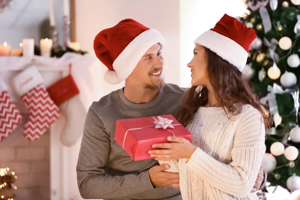 Bonito Jovem Casal Chapéus Papai Noel Com Presente Natal Casa — Fotografia de Stock