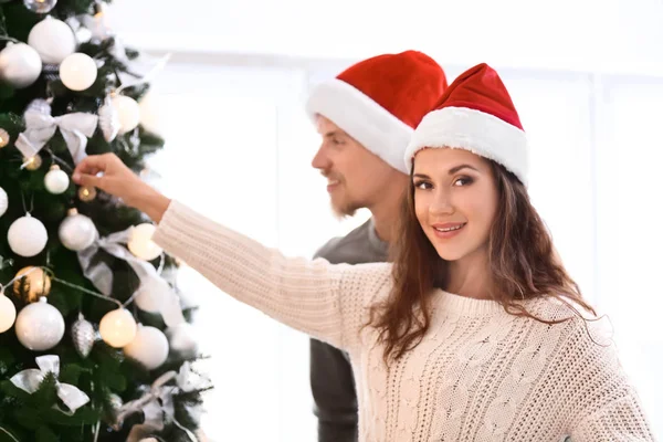 Cute Young Couple Santa Hats Decorating Christmas Tree Home — Stock Photo, Image