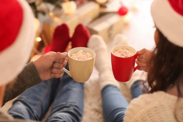 Cute young couple drinking hot chocolate on Christmas eve at home