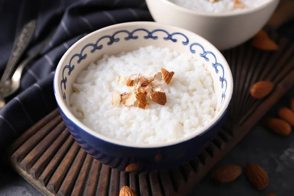 Bowl with delicious rice pudding and nuts on board