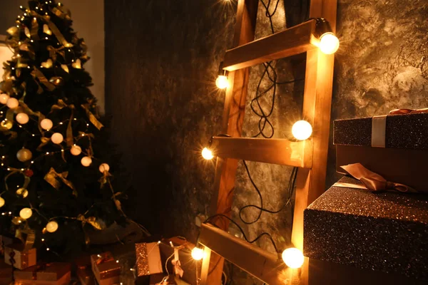 木制梯子与圣诞花环和礼物在黑暗的墙壁附近在室内 — 图库照片